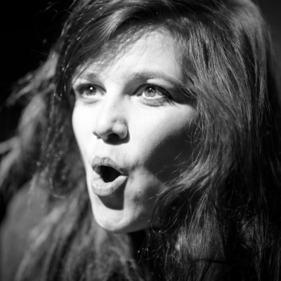 A black and white photo of a white woman singing opera